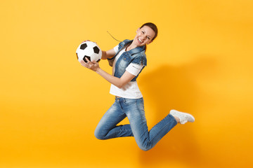 Fototapeta na wymiar Young fun expressive European woman football fan jumping in air, cheer up support team, holding soccer ball isolated on yellow background. Sport, play football, cheer, fans people lifestyle concept.
