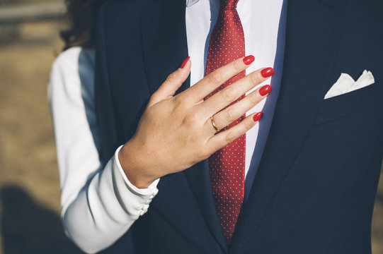 Bride hand with red nails, embracing the chest of the groom