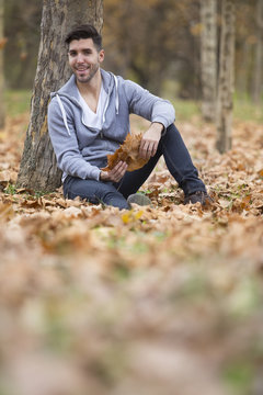 Handsome man in nature holding autumn leaves. Copy space
