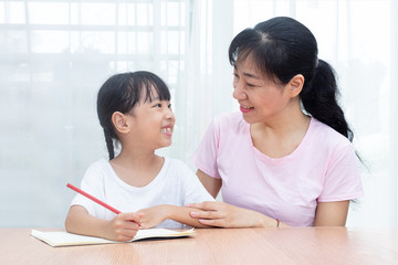 Asian Chinese mother teaching daughter doing homework