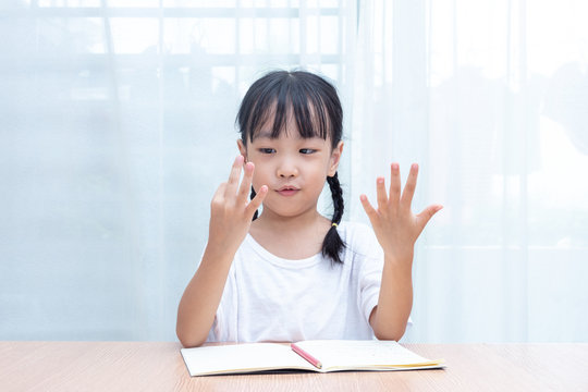 Asian little Chinese Girl doing mathematics by counting fingers