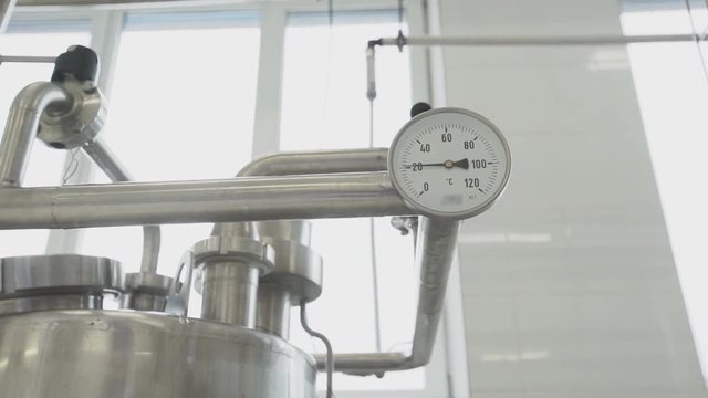 Small white thermometer of pasteurizer with marks from zero to one hundred and twenty froze at around twenty degrees Celsius