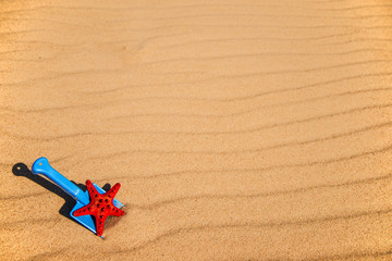 beach with kid toys shovel, bucket and red sea star