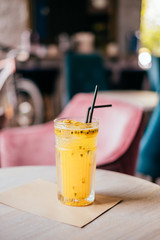 Beautiful glass of yellow passionfruit lemonade on the wooden table. Flatlay style, spotted on the city cafe.