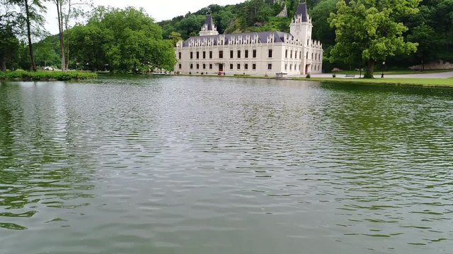 4K Drone footage. Flying from the lake to the beautiful old castle with park.