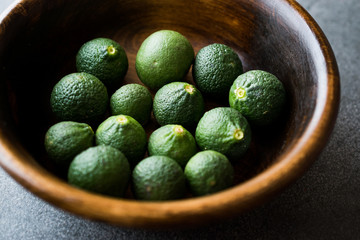 Immature Unripe Organic Green Limes in Wooden Bowl.