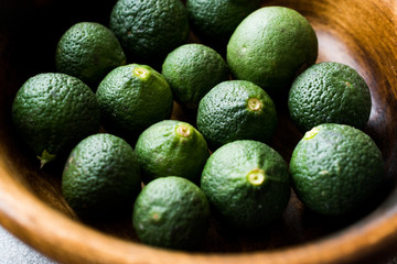 Immature Unripe Organic Green Limes in Wooden Bowl.