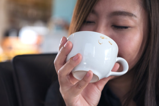 Closeup image of Asian woman smelling and drinking hot coffee with feeling good in cafe
