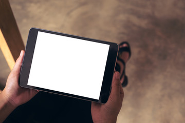 Top view mockup image of woman's hands holding black tablet pc with blank white desktop screen