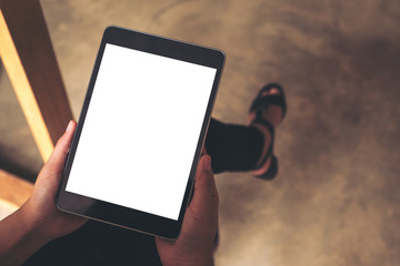 Top view mockup image of woman's hands holding black tablet pc with blank white desktop screen