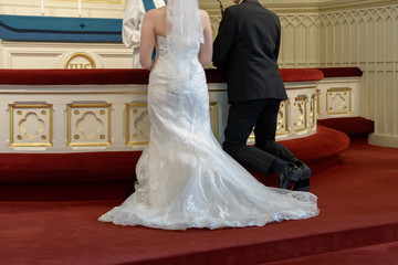 Bride and groom kneel on altar and saying oaths during wedding ceremony