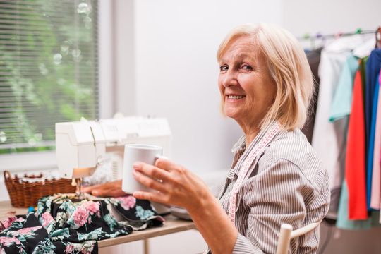 Adult woman is sewing in her studio. 