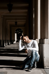 Obraz premium A young man travels through the streets of the city. Boy in sunglasses Stylish man near the building. The man sits on a whip. Beard and hair in a stylish guy.