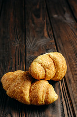 two fresh croissants on dark wooden table place for text