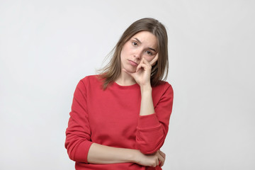 Pretty caucasian woman in red sweater is tired or bored. She do not want to work or study
