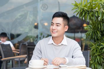 Happy young man working on laptop computer during coffee break in cafe bar