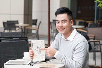 Cheerful asian businessman showing creative idea documents