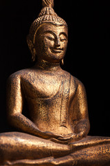 The gilded statue of smilin Buddha, in Southeast Asia style.  Isolated on black background.
