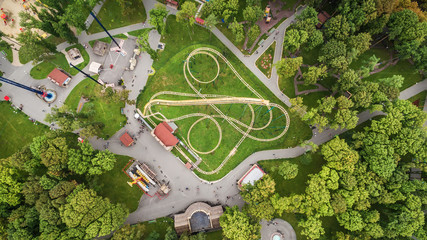 The aerial top view on the attraction "roller coaster" located in the center of the city park of the Ukrainian city of Kharkiv, among trees.