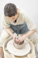 Fototapeta na wymiar Woman hands makes clay pot on the pottery wheel