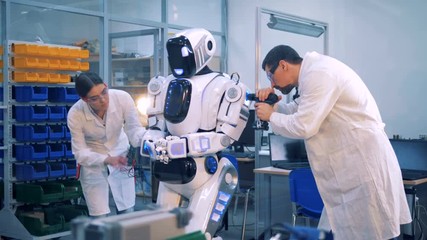Workers repair a robot in a laboratory room.