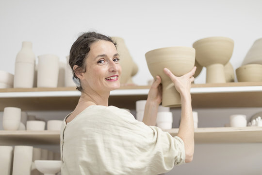 Ceramist woman holding a potter in her studio
