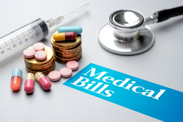 Medical bills concept. Coins, pills, stethoscope, syringe on grey background.
