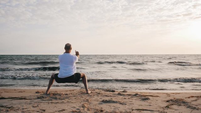 Man standing in horse stance Ma Bu while morning training WuShu on sea shore