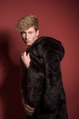 A man in black fur on red background. Sexy body