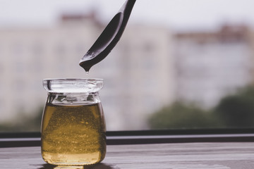 Honey in glass jar and wooden spoon closeup.