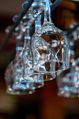 Empty glasses set in restaurant. Wine glasses hang on the counter in the bar.