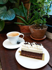 Chocolate cake with a cup of hot coffee on wooden table.