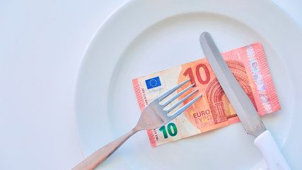 Euro banknote on a white plate, cash in Europe, the cost of lunch in the restaurant.