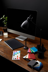 close up view of graphic designer workplace with colorful pallet, graphic tablet, blank computer screen and lamp on wooden surface