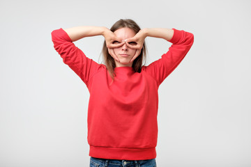 Fototapeta premium Pretty girl holding fingers near eyes like glasses: mask like super hero