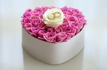 Wedding rings with diamonds lie waiting for the wedding moment, on the pink ceremonial small pillow made from rose blooms.