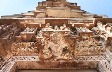 View of deity`s, and tops of the Khajuraho temple complex against the background of the blue sky. 