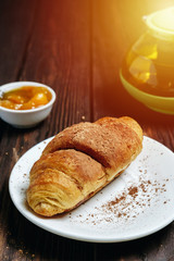 fresh croissants with jam on dark wooden table and tea with rosemary, sunshine, chocolate on food