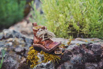 Luxury wedding rings near boot on stone and moss