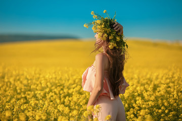Naklejka na ściany i meble Free happy young woman in rape field enjoying life. Pretty brunette with long healthy hair. Carefree girl over yellow field and blue sky. Countryside landscape Lifestyle.