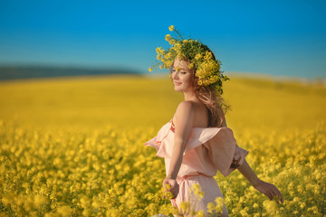 Naklejka na ściany i meble Free happy young woman in rape field enjoying life. Pretty brunette with long healthy hair. Carefree girl over yellow field and blue sky. Countryside landscape Lifestyle.