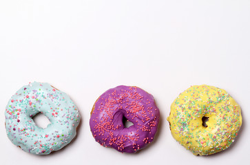 Multicolored glazed donuts on a white background. Place for text