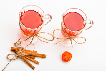 Mulled wine or hot beverage in glasses with decoration and cinnamon sticks. Glasses with mulled wine or hot drink tied with twine string on white background, close up. Hot drinks concept