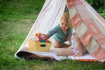 Smeared children play in nature in an improvised house. Homemade tent, hut, for fun girls and boys. Camping © SVIATLANA