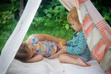 Smeared children play in nature in an improvised house. Homemade tent, hut, for fun girls and boys. Camping © SVIATLANA