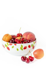 Eine Schüssel mit Kirschen und Pfirsiche vor einem weißen Hintergrund