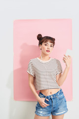 Emotive adorable teenage ginger girl smiling while listening to music via earphones and cute smile over pink background.