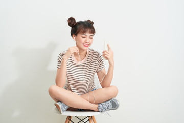 Cheerful young woman using smartphone with headphones over pink background
