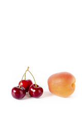 Kirschen und Pfirsich vor einem weißen Hintergrund