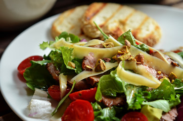 Salad with pork tenderloin and cherry tomatoes on a white plate